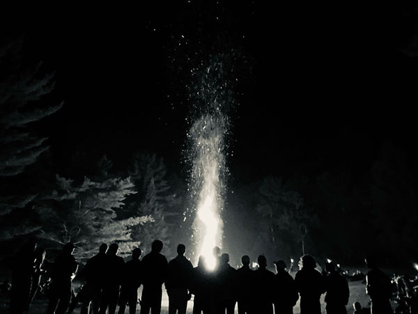 A group surrounds the bonfire at Camp Menominee
